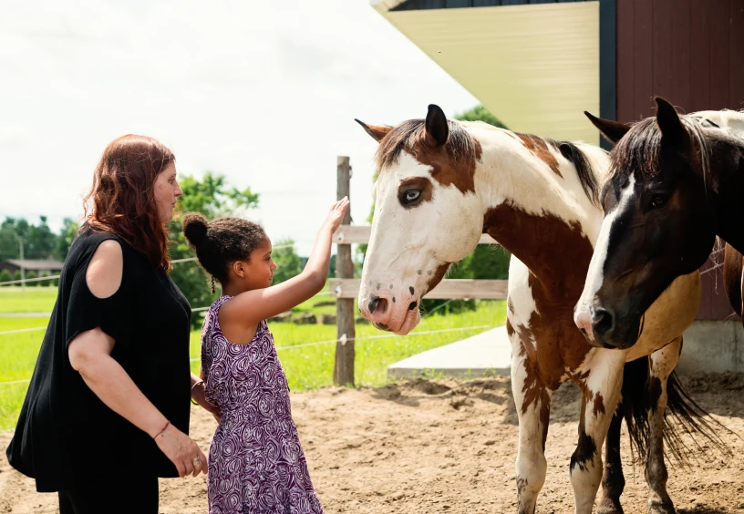 Child and woman interacting with horses